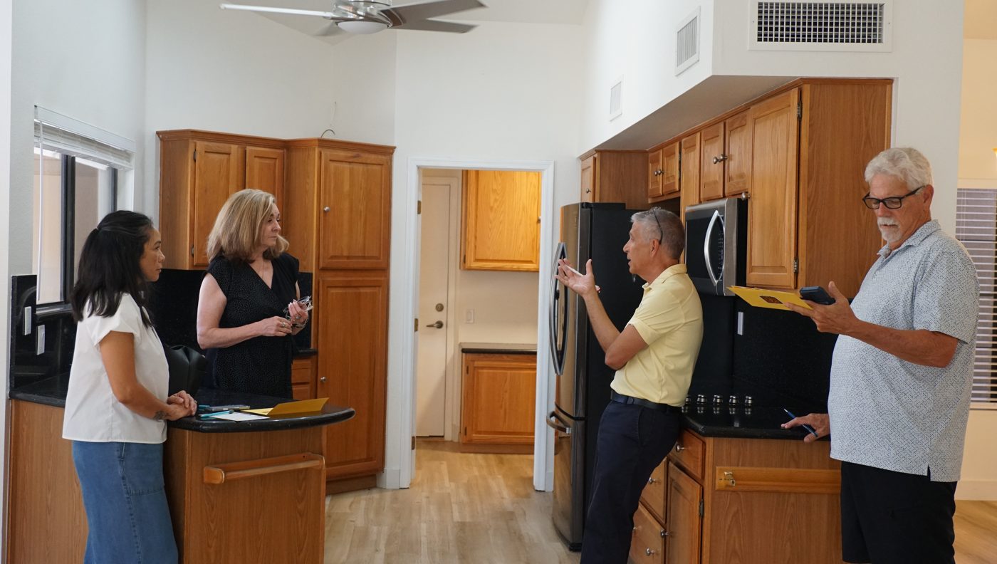 An agent making a point about a kitchen while three other agents listen.